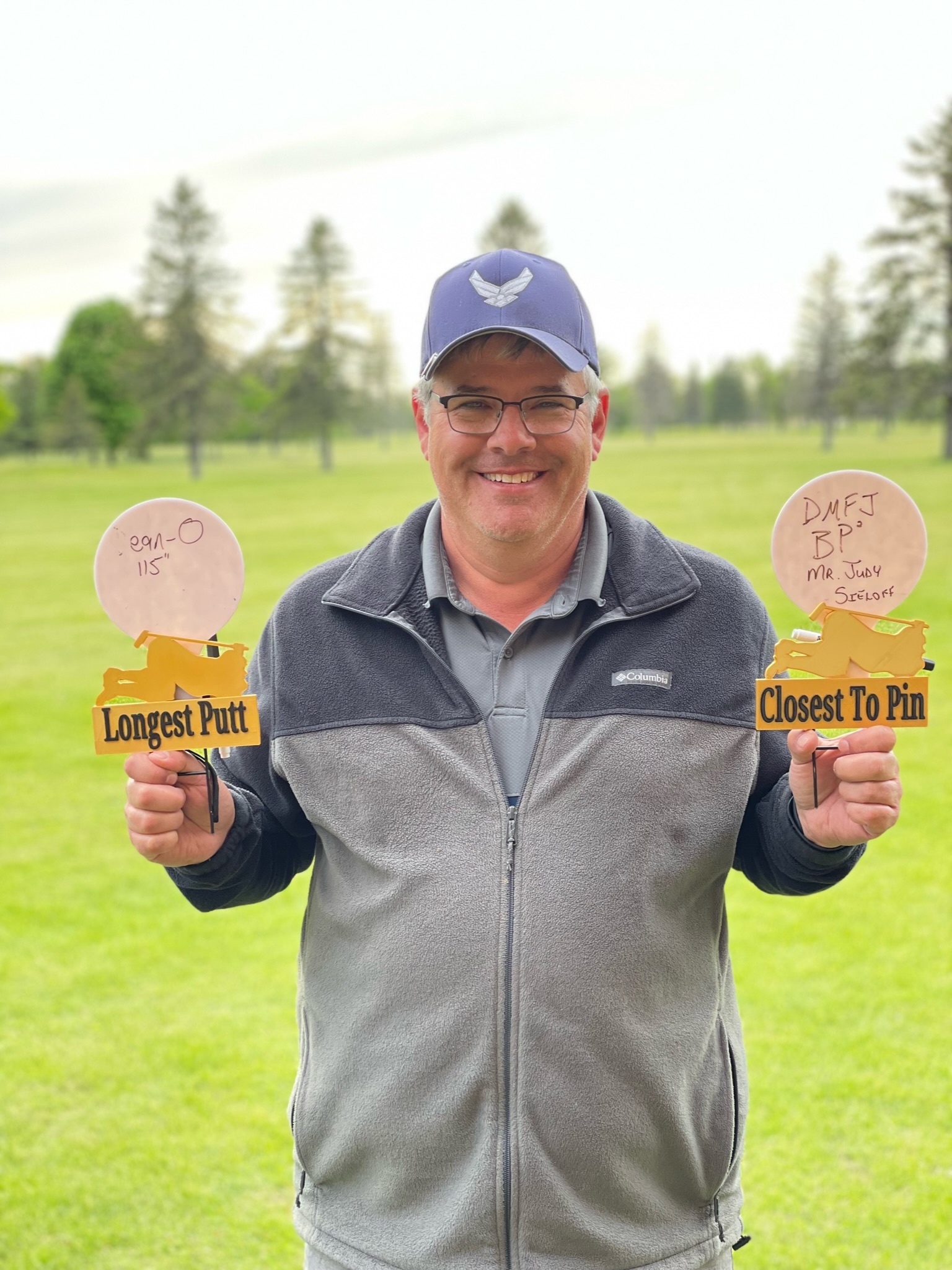 Dean Johnson holding the on-course prize markers after winning the closest-to-the-pin prizes