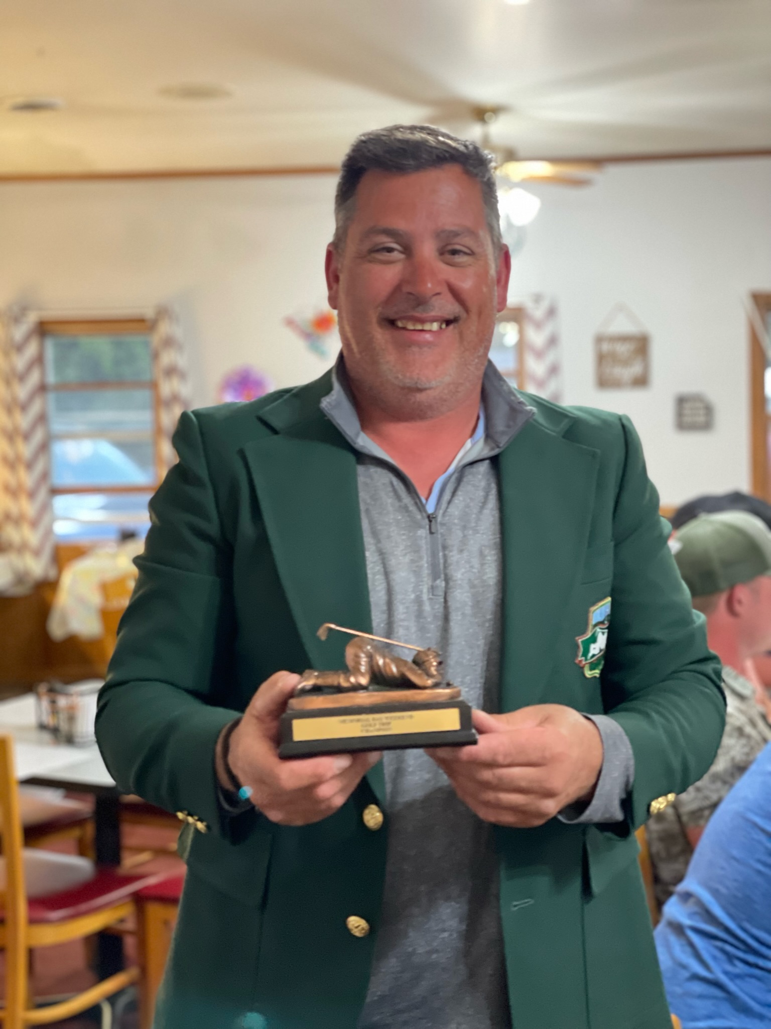 Kevin Pacholski in the green jacket holding the championship trophy after winning on his first trip